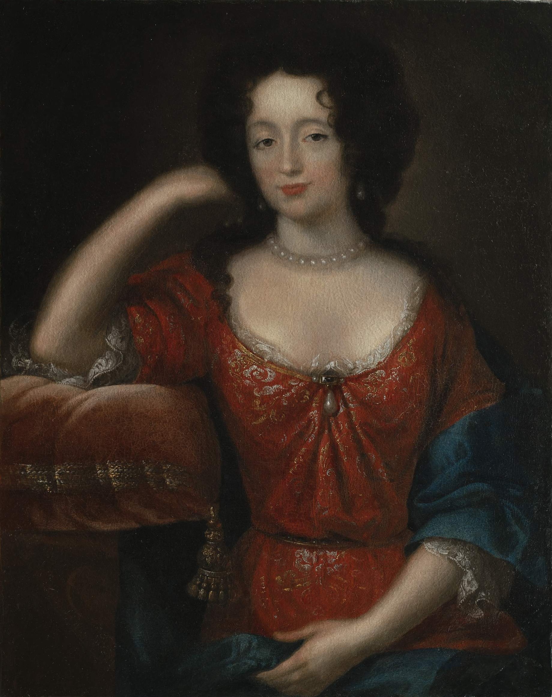 Obraz przedstawia piękną kobietę z ciemnymi włosami, w czerwonej sukni z głębokim dekoltem i naszyjniku z pereł. To Maria Kazimiera, królowa. Lekko uśmiechnięta, patrzy wprost na widza, opiera głowę na ręce spoczywającej na poduszce