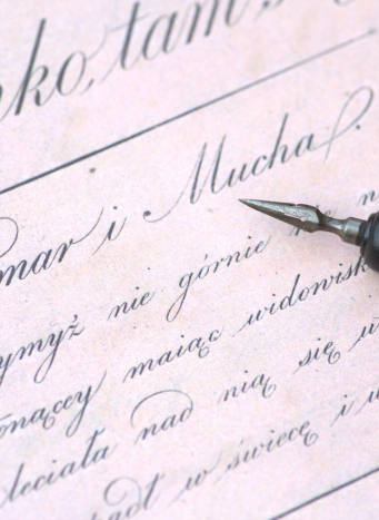 Kartka papieru z odręcznie napisanym tekstem na której leży stalówka.