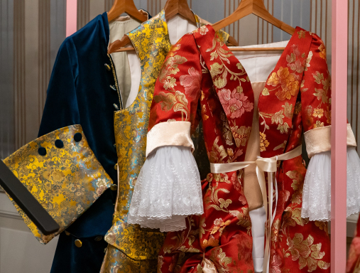 Stroje historyczne wiszące na wieszakach.